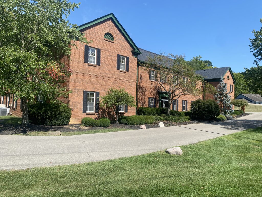 Two story red brick building with green trim